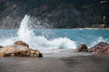 Dalgalar kayalık deniz kıyısına çarpıyor. Cinque Terre 'de. Monterosso, liman, sahil ve antik köy.                                  