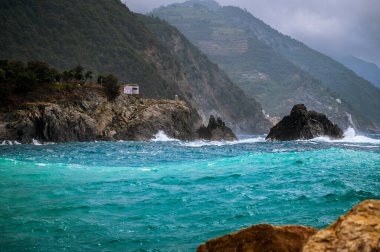 Dalgalar kayalık deniz kıyısına çarpıyor. Cinque Terre 'de. Monterosso, liman, sahil ve antik köy.                                  