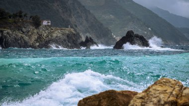 Dalgalar kayalık deniz kıyısına çarpıyor. Cinque Terre 'de. Monterosso, liman, sahil ve antik köy.                                  