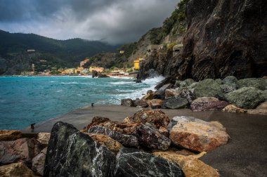 Dalgalar kayalık deniz kıyısına çarpıyor. Cinque Terre 'de. Monterosso, liman, sahil ve antik köy.                                  