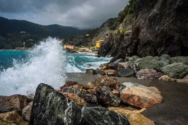 Dalgalar kayalık deniz kıyısına çarpıyor. Cinque Terre 'de. Monterosso, liman, sahil ve antik köy.                                  