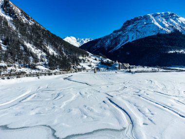 Reschensee 'deki (Resia Gölü) ünlü batık kilise kulesinin bulunduğu Alpler' deki kış manzarası Güney Tyrol (İtalyan Alpleri) ve Avusturya sınırı üzerindedir..