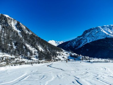 Reschensee 'deki (Resia Gölü) ünlü batık kilise kulesinin bulunduğu Alpler' deki kış manzarası Güney Tyrol (İtalyan Alpleri) ve Avusturya sınırı üzerindedir..