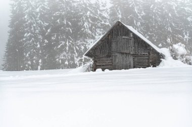 Kışın dağlarda ahşap kulübesi olan güzel bir manzara. 