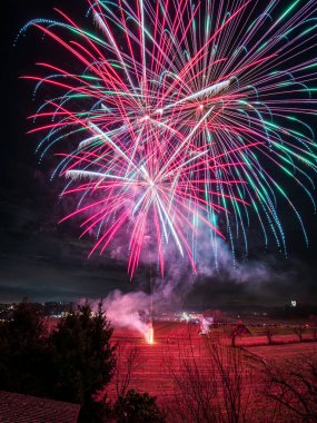 Bir dizi renkte parlak havai fişekler patlıyor ve gece gökyüzünü aydınlatıyor. 