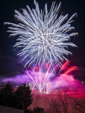 Bir dizi renkte parlak havai fişekler patlıyor ve gece gökyüzünü aydınlatıyor. 