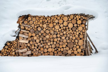 Sappada, Veneto, İtalya 'da kış kar yağışı sırasında istiflenmiş ahşap kütükler 