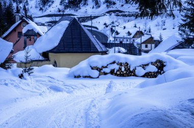 Tarvisio. Julian Alplerinin eteklerinde kışın Riofreddo vadisinde karlı evler