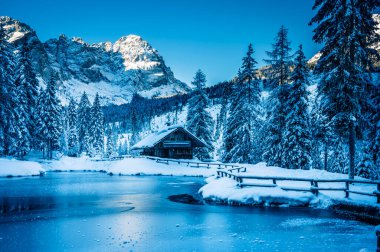Göldeki eski kulübe. Kış dağlarında ormanla çevrili. 