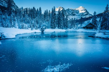 Göldeki eski kulübe. Kış dağlarında ormanla çevrili. 