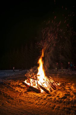 Kamp ateşi etrafında dans eden insanlar Sauris 'ten Tahta Maskelerle Antik Karnaval' ı kutluyorlar. Baharın gelişi için Karnianın Büyüsü