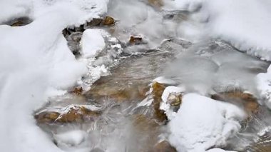 Kış dağlarında akan suyla donmuş akarsu 