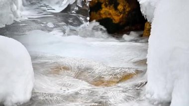 Kış dağlarında akan suyla donmuş akarsu 