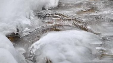 Kış dağlarında akan suyla donmuş akarsu 
