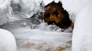 Kış dağlarında akan suyla donmuş akarsu 