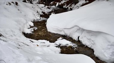 Kış dağlarında akan suyla donmuş akarsu 