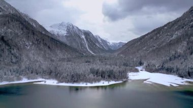 Kışın Lago del Predil 'in insansız hava aracından manzara, İtalya' da dağlarla çevrili göl. 