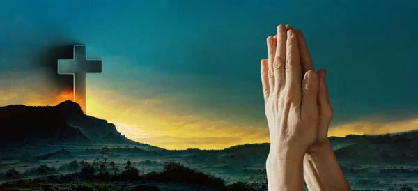 Hands in pray against Easter cross and sunset landscape. Copy space. Shining cross on Calvary hill, sunrise sky background. Faith in Jesus Christ. Christianity. Church worship, salvation concept.