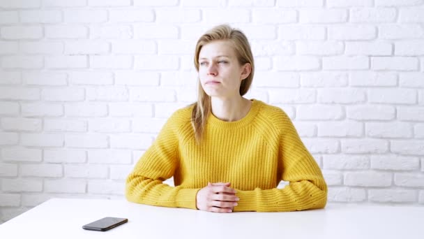思考の深いテーブルに座って 黄色のセーターで思慮深い女性は スマートフォンを使用して — ストック動画