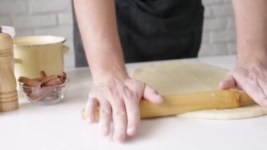 Erkek şefin tarçınlı rulo yaptığı seçmeli odak noktası, arka planda ışıklar olan noel ağacı, şenlikli yemekler.