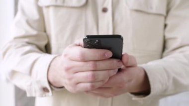man in beige shirt using smartphone, holding in hands