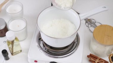 Creative occupation of candle making, pouring and melting soy wax in the pot and stirring it