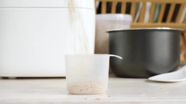Kahverengi pirinç plastik ölçü kabına düşer, mutfakta pilav pişirmeye hazırdır. Sağlıklı gıda konsepti