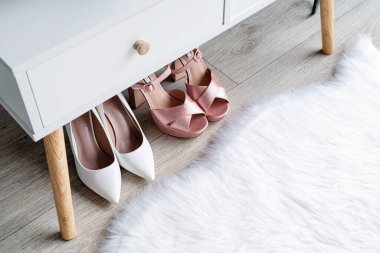 Stylish light room interior with elegant vanity table and plants, beauty and fashion. closeup of elegant high heel shoes standing under dressing table, mockup