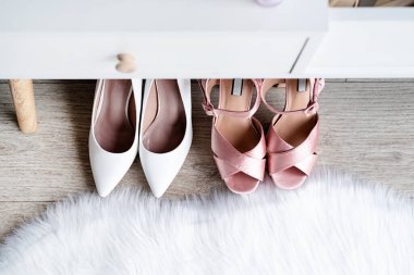Stylish light room interior with elegant vanity table and plants, beauty and fashion. closeup of elegant high heel shoes standing under dressing table, mockup