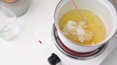 Creative occupation of candle making, pouring and melting soy wax in the pot and stirring it