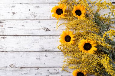 Frame of yellow mimosa flowers bouquet on wooden solid bakground. Spring concept. Flat lay. Top view, banner