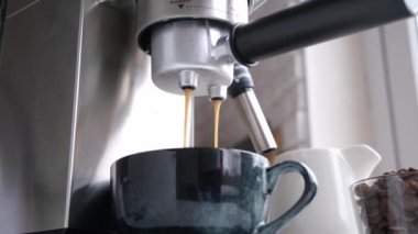 male hands holding portafilter and making fresh aromatic coffee at home using a modern coffee maker
