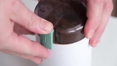 male hands holding portafilter and making fresh aromatic coffee at home using a modern coffee maker