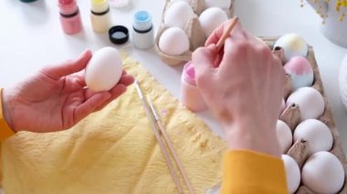 Bayram için paskalya yumurtalarını pastel renklerle boyayan bir kadın. Merhaba bahar konsepti, Paskalya hazırlama konsepti.