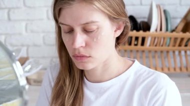 Günlük makyaj. Doğal güzellik. Makyajsız genç bir kadının aynaya bakıp temel krem sürmesi, rutin makyajı. sarı mimoza çiçekleri ve arka plan