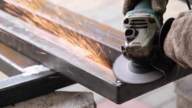 Çelik kiriş üzerinde elektrikli öğütücüyle çalışan bir adam. Kıvılcımlar uçuşuyor Elektrik öğütme. Pası sil