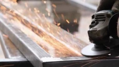 Çelik kiriş üzerinde elektrikli öğütücüyle çalışan bir adam. Kıvılcımlar uçuşuyor Elektrik öğütme. Pası sil