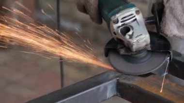 Çelik kiriş üzerinde elektrikli öğütücüyle çalışan bir adam. Kıvılcımlar uçuşuyor Elektrik öğütme. Pası sil