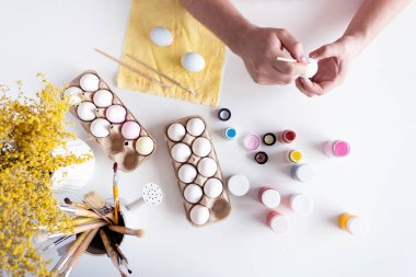 Bahar tatili, Paskalya. Ev mutfağında paskalya yumurtası boyayan sade gömlekli bir adam.