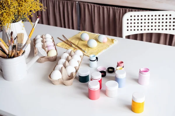 Spring holidays, Easter. Table with easter colored eggs and paints at home kitchen, childern craft