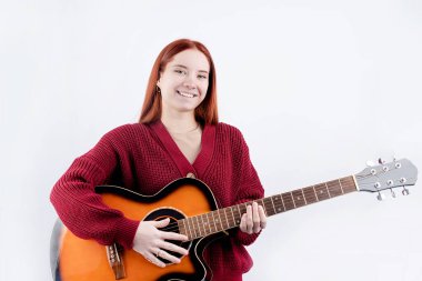 Beyaz arka planda izole edilmiş akustik gitar çalan beyaz saçlı genç bir kadın. Gitar kursları reklamı