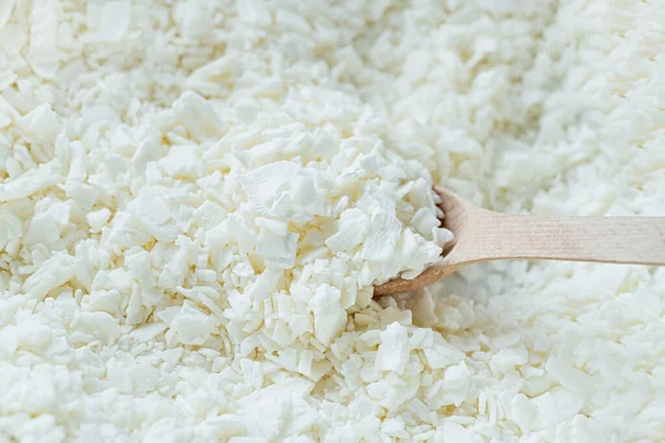 stock image Creative hobby of candle making at home. closeup of wooden spoon in white soy wax flakes. Natural soywax texture