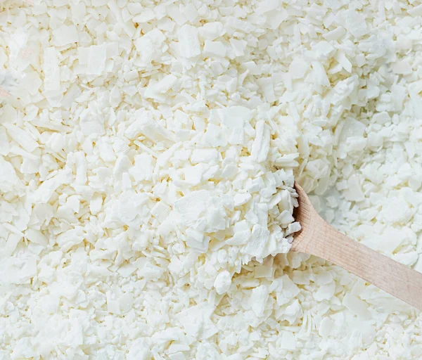 Stock image Creative hobby of candle making at home. closeup of wooden spoon in white soy wax flakes. Natural soywax texture