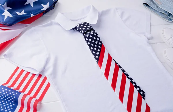 USA Memorial day, Presidents day, Veterans day, Labor day, or 4th of July celebration. Mockup design white polo t shirt for logo, top view on white wooden background with US flag, shoes and jeans