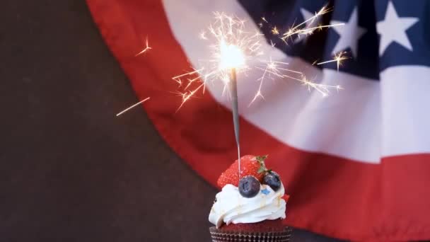 7月4日お祝い ブルーベリーとストロベリーの甘いカップケーキとアメリカの国旗の背景に輝く — ストック動画