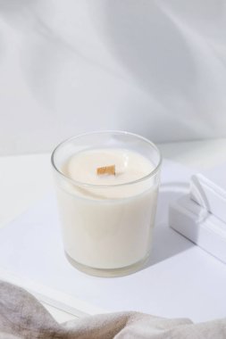 Kavanozda aromatik mum olan estetik bir kompozisyon. Doğal olarak balmumu mumunu taklit et. Beyaz kitaplı el yapımı mum. Model tasarımı