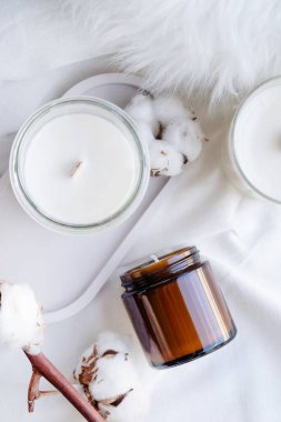 Beyaz kavanozdaki soya aromalı mum ve pamuk dalı. Mum modelleme tasarımı. Doğal olarak balmumu mumunu taklit et..