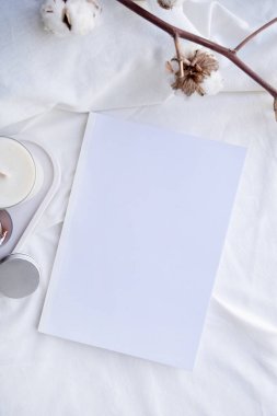 Beyaz kavanozdaki soya aromalı mum ve pamuk dalı. Mum ve kitap tasarımı. Doğal olarak balmumu mumunu taklit et..