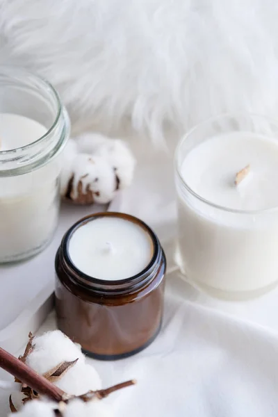 stock image Soy wax aroma candle in white jar on bed with cotton branch. Candle mockup design. Mockup soy wax candle in natural style.