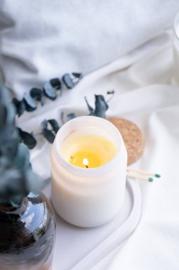 Beyaz kavanozda soya aromalı mum ve okaliptüs yaprakları. Mum modelleme tasarımı. Doğal olarak balmumu mumunu taklit et..